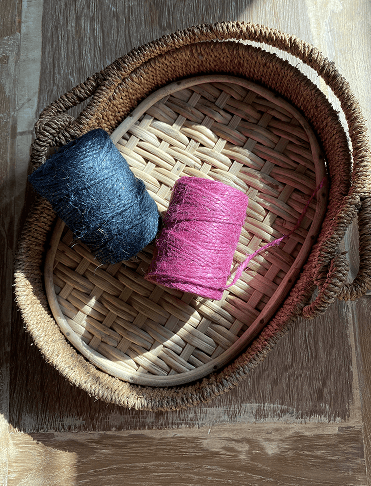 Traditional woven basket with spools of colorful jute yarn